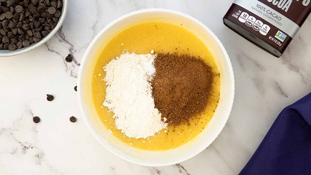 person whisking cocoa, flour, salt, and baking powder together in mixing bowl