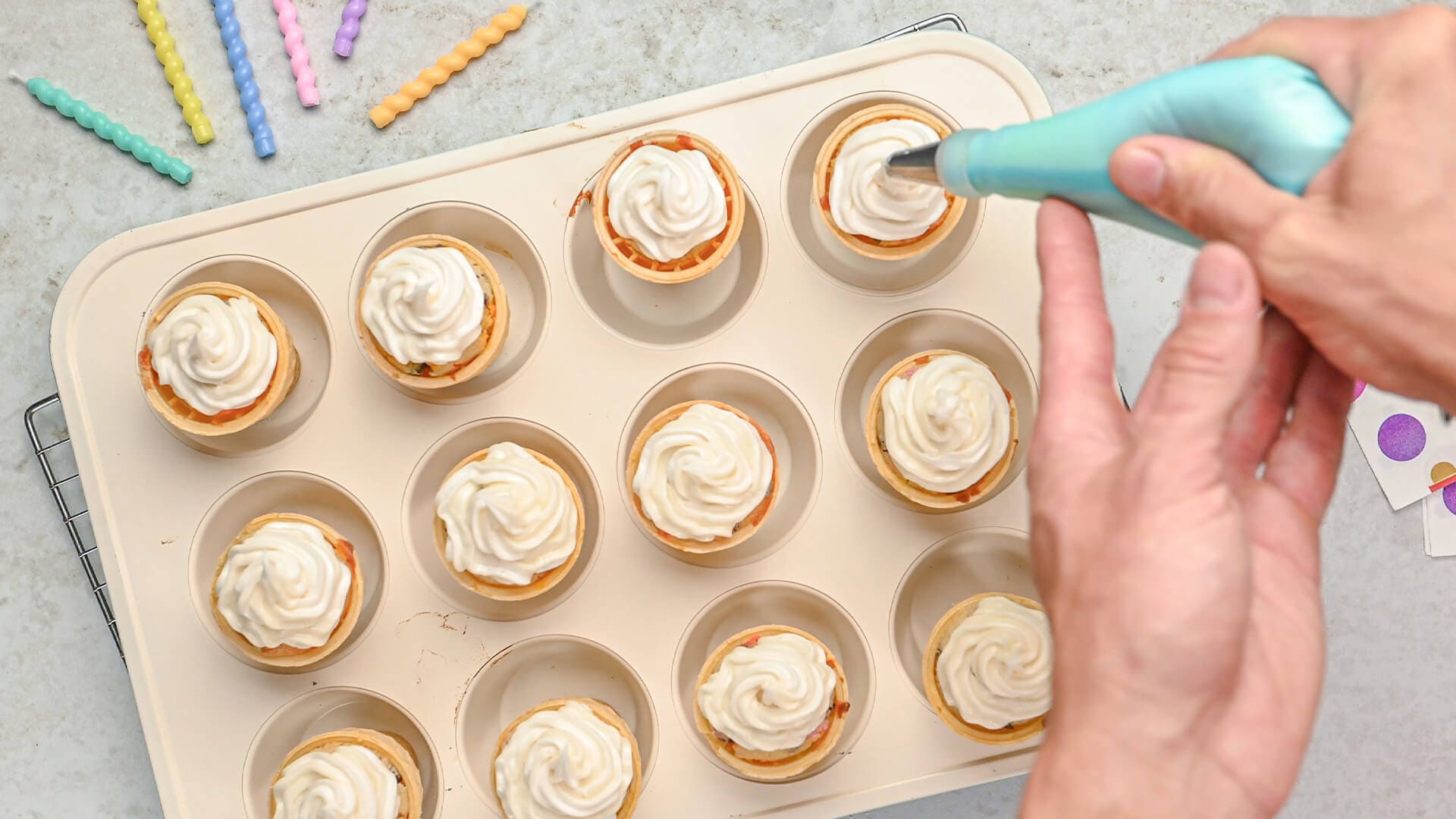 icing being piped onto cupcakes