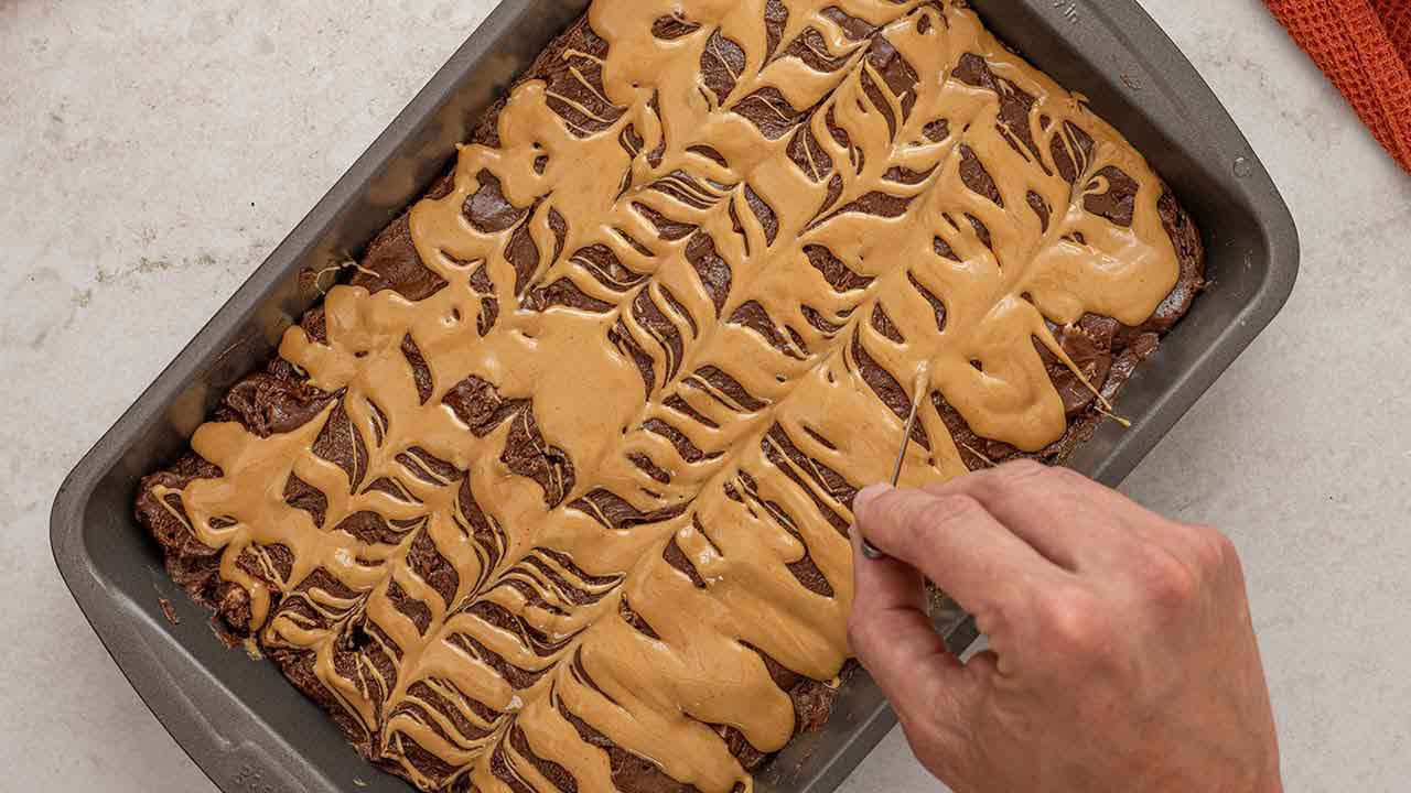 using a toothpick to swirl the top of the brownie batter