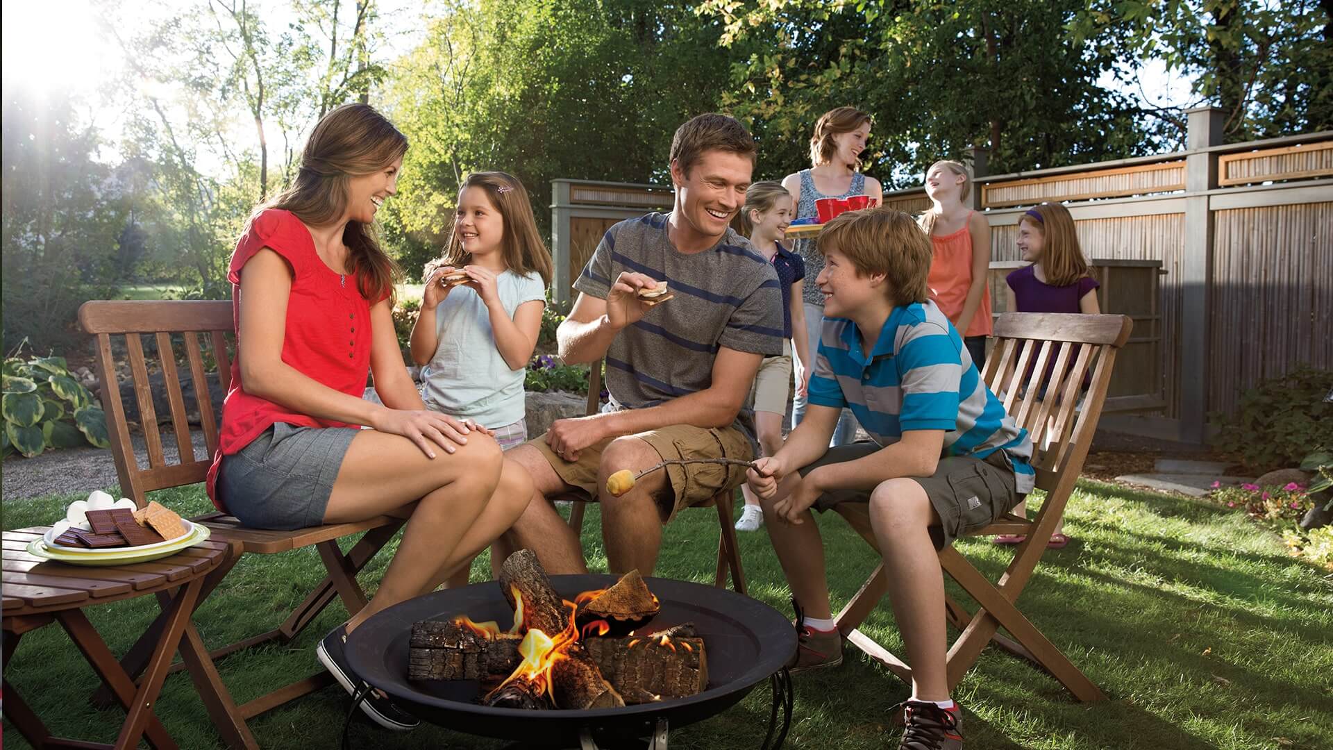 backyard party with family sitting around fire pit