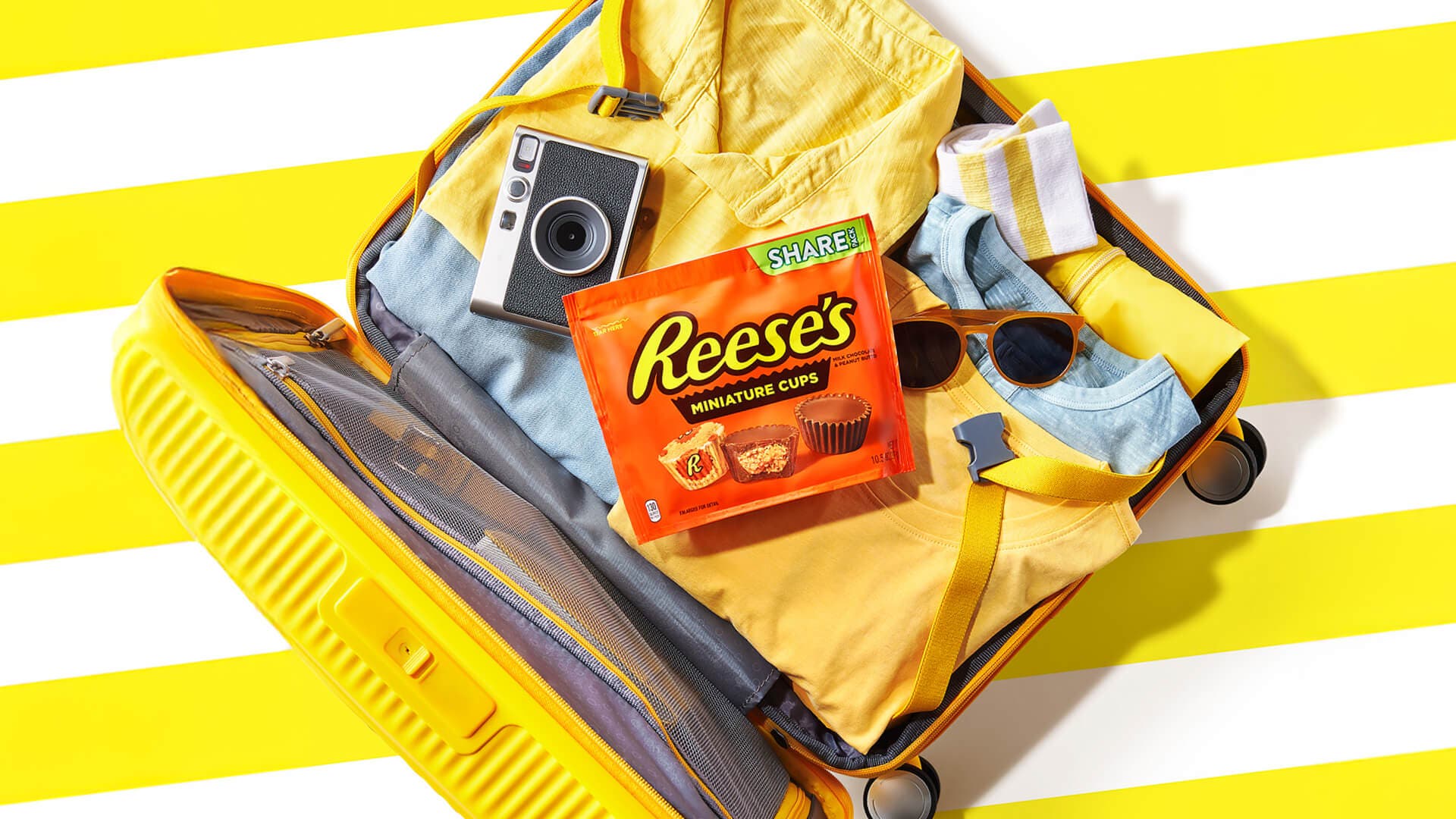 packed yellow suitcase with a share bag of reeses cups on top