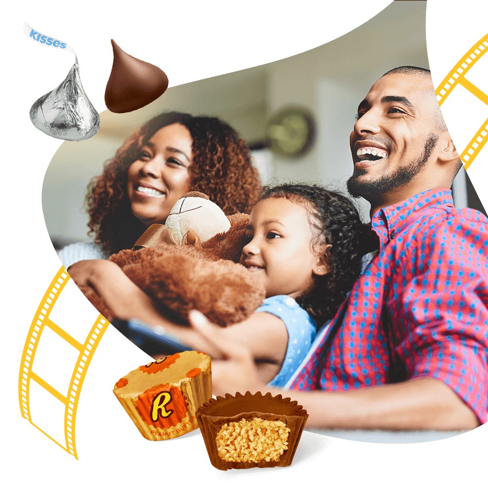 smiling family sitting on couch with hersheys kisses and reeses peanut butter cups